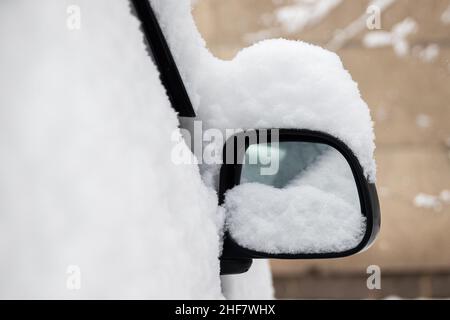 Auto Rückspiegel bedeckt mit Schnee in der Winterstadt. Stockfoto