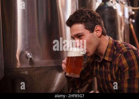 Nahaufnahme eines professionellen Brauers, der in seiner Mikrobrauerei köstliches Craft-Bier frisch gebraut trinkt Stockfoto