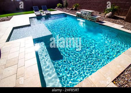 Hintere Gartenliegen Rund Um Den Swimmingpool Mit Wasserfall Stockfoto