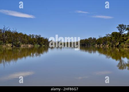 Flacher, ruhiger, breiter, brauner Murray River an einem heißen Sommertag mit Wolkenfetzen, die sich im Wasser spiegeln Stockfoto