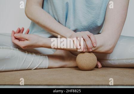 Unterarmmuskulatur myofasziale Freisetzung mit großer Kork-Massagekugel auf Kork-Yoga-Matte. Konzept: Selbstversorgung zu Hause Stockfoto