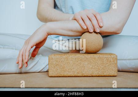 Unterarmmuskulatur myofasziale Freisetzung mit Massageball auf Korkblock. Konzept: Selbstpflege zu Hause, nachhaltige und umweltfreundliche Requisiten Stockfoto