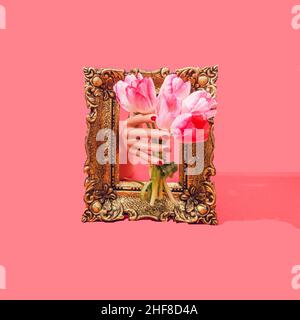 Eine Damenhand, die einen Strauß rosa Tulpen durch einen goldenen Vintage-Rahmen bietet. Heller roter Hintergrund. Surreales künstlerisches Konzept für Valentine's oder Mo Stockfoto