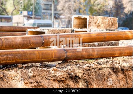 Bauarbeiten an großen Eisenrohren am ausgegrabenen Graben. Austausch von Heizungsrohren in der Stadt Stockfoto