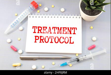 Das Wort Treatment Protocol ist auf weißem Papier auf einem grauen Hintergrund in der Nähe eines Stethoskops geschrieben. Medizinisches Konzept Stockfoto