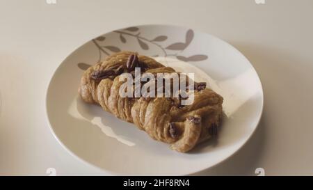 Nahaufnahme von frisch gebackenen Croissants und süßen Brötchen, die auf Keramikplatten in einer Reihe auf weißem Tischhintergrund liegen. Bäckereiprodukte und Lebensmittelkonzept. Stockfoto