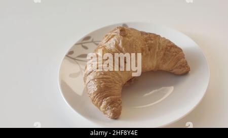 Nahaufnahme von frisch gebackenen Croissants und süßen Brötchen, die auf Keramikplatten in einer Reihe auf weißem Tischhintergrund liegen. Bäckereiprodukte und Lebensmittelkonzept. Stockfoto