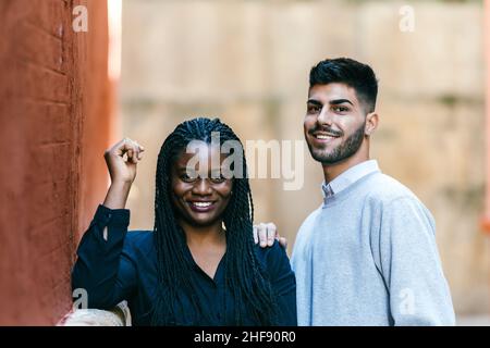 Multiethnische Freunde stehen lächelnd vor der Kamera im Freien Stockfoto