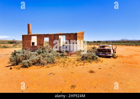 Ruinen eines alten historischen Backsteinhauses mit Trümmern eines alten rustikalen Autos in Silverton im australischen Outback. Stockfoto