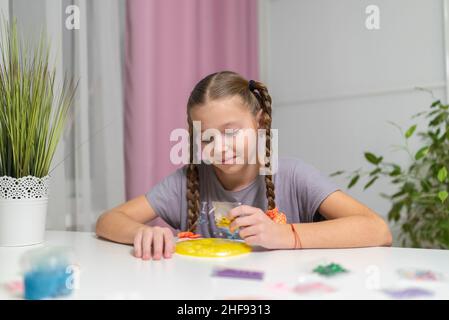 Mädchen spielen mit gelben Schleim am Tisch Spaß zu Hause. Stockfoto