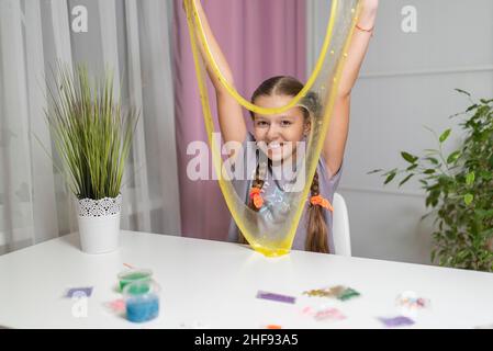 Mädchen spielen mit gelben Schleim strecken und Spaß zu Hause Stockfoto
