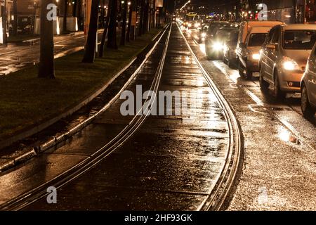 Nasse Trolleyschienen im Licht und auf den Straßen reflektieren das Licht Stockfoto