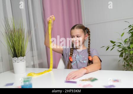 Mädchen spielen mit gelben Schleim strecken und Spaß zu Hause Stockfoto