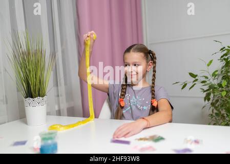 Mädchen spielen mit gelben Schleim strecken und Spaß zu Hause Stockfoto