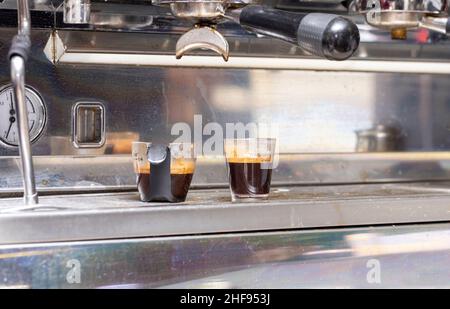 Kaffee-Shots, die an einer Espressomaschine in einem Kaffeehaus gegossen werden Stockfoto
