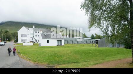 Zwei Wanderer laufen hinter der Rückseite der Brücke des Orchy Hotels, eine aktualisierte 1930s, während Wolken auf dem Hügel im Hintergrund absinken. Stockfoto