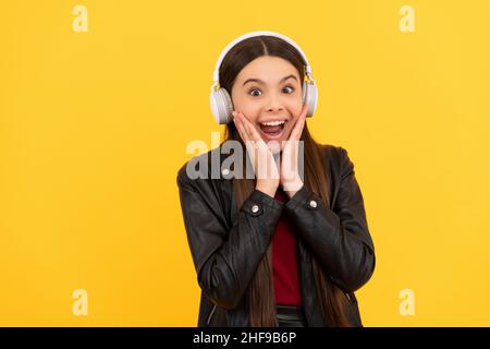 Stauntes Kind in Kopfhörern auf gelbem Hintergrund, Musik Stockfoto