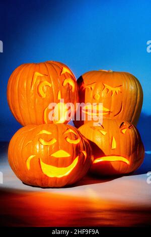 Vier leuchtende Halloween Jack-o-Laternen zeigen eine Vielzahl von Ausdrücken. Stockfoto