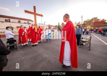 Im Rahmen einer Messe im Freien, bilden multirassisch getragente Priester eine Prozession, während sie ein Kreuz vor ihrer Gemeinde auf dem Parkplatz eines Southers laufen Stockfoto