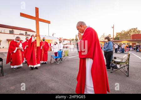 Im Rahmen einer Messe im Freien, bilden multirassisch getragente Priester eine Prozession, während sie ein Kreuz vor ihrer Gemeinde auf dem Parkplatz eines Southers laufen Stockfoto