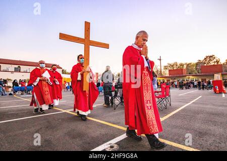 Im Rahmen einer Messe im Freien, bilden multirassisch getragente Priester eine Prozession, während sie ein Kreuz vor ihrer Gemeinde auf dem Parkplatz eines Southers laufen Stockfoto