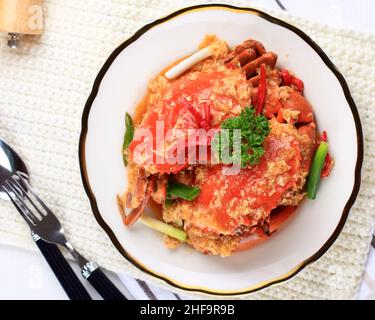 Chilischlammkrabbe, Krabbe mit singapurischer Sauce, besondere Küche Singapurs. Serviert auf weißem Teller Stockfoto