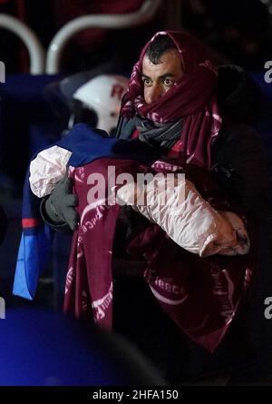 Ein Mann trägt ein Baby, da eine Gruppe von Menschen, die als Migranten gelten, nach Dover, Kent, gebracht wird, nachdem sie von der RNLI nach einem kleinen Bootsunfall im Kanal gerettet wurde. Bilddatum: Samstag, 15. Januar 2022. Stockfoto
