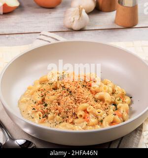 Mac und Käse mit Semmelbröseln, Oregano Garnish, auf der Oberfläche aus weißem Holz Stockfoto