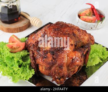 Ausgewählter Fokus Spicy Honey Rösted Whole Chicken, Typisches Indonesisches Essen Namens Ayam Bakar Bumbu Rujak. Javanische Küche aus Huhn mit roten Basi Stockfoto