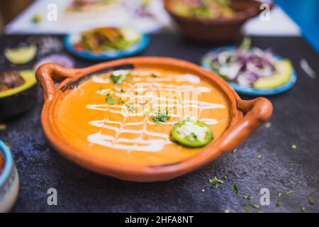 Köstliche Suppe im traditionellen Tontopf über dunkler Oberfläche Stockfoto