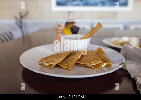 Teller mit traditionellen Quesadillas und Tasse Bohnen auf braunem Tisch Stockfoto