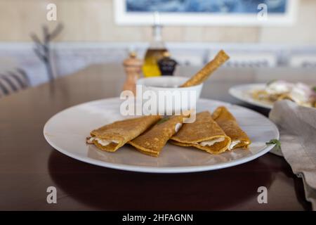 Teller mit traditionellen Quesadillas und Tasse Bohnen auf braunem Tisch Stockfoto