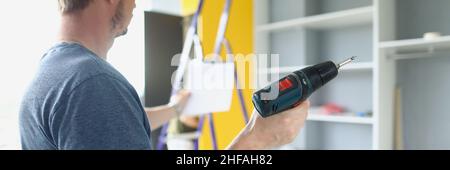 Mann, der Schraubendreher hält und auf den Schrank schaut Stockfoto