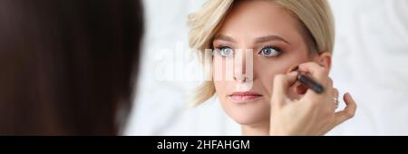 Meister Make-up-Künstler macht Make-up zu blonden Frau Stockfoto