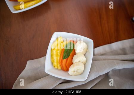 Quadratischer Teller mit frischen Obstscheiben auf braunem Tisch Stockfoto
