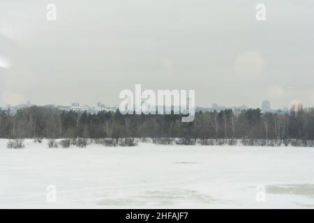 Panoramablick auf das Kiewer Höhlenkloster im Winter. Fluss, Kirche der Geburt der Jungfrau Maria, Glockenturm an den Far Caves. Stockfoto