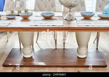 Luxuriöser Vintage-Esstisch aus massivem Nussbaum- und Furnierholz mit festlichem Ambiente und Sesseln in der Nähe des Fensters in einem geräumigen Zimmer aus nächster Nähe Stockfoto