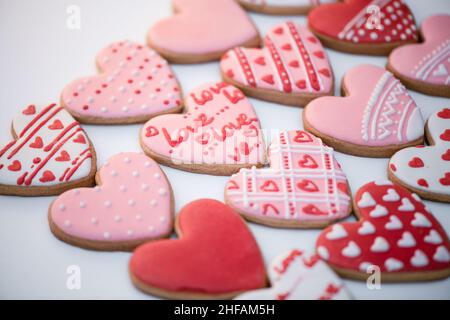 Draufsicht hausgemachter Lebkuchen Valentinstag mit Inschrift - Liebe, Cookies Herz Formen mit farbigen königlichen Glasur und bunten Mustern verziert Stockfoto