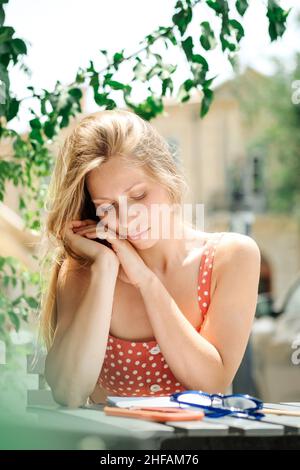 Traurig gelangweilt junge kaukasische, Millennial oder Gen z Frau mit langen Brünette sprechen auf Smartphone in der Hand in modernen Outdoor-Café.Hipster Influencer über soziale Netzwerke. Stockfoto