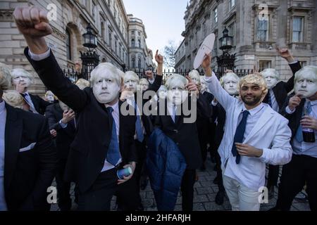 London, Großbritannien. 14. Januar 2022. Flash-Mob von „partygate“-Anti-Boris Johnson-Demonstranten mit blonden Perücken und Boris Johnson-Masken und Anzügen versammelten sich vor der Downing Street, tranken Bier und Wein, während sie zu Techno-Musik tanzten und skandierten: „Dies ist ein Arbeitsevent!“ Nachdem der britische Premierminister wegen der Abhaltung einer Getränkeparty in der Downing Street Nr.10 bei verschiedenen Gelegenheiten untersucht wurde, um die COVID-Sperrbeschränkungen während der Pandemie zu brechen.Freitag, 14th. Januar 2022. Whitehall, London, England, Vereinigtes Königreich Kredit: Jeff Gilbert/Alamy Live News Stockfoto