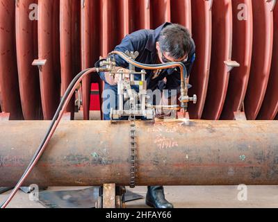 Arbeiter schneidet ein großes Stahlrohr mit dem Oxyacetylen-Schneidverfahren. Stockfoto