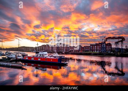 Sonnenaufgang am Preston Docks, Lancashire. Wetter in Großbritannien. 15 Jan, 2022., außergewöhnliche Cirrocumulus-Wolkenformationen, die sich an einem kalten Januarmorgen bei Sonnenaufgang in Preston-Docks bei kühltem Wind widerspiegeln. Cirrocumulus und Altocumulus rote Wolken enthalten überkühltes Wasser, das noch nicht zu Eiskristallen geworden ist. Das Wasser bleibt in der Atmosphäre schweben, bis sich schließlich Eiskristalle bilden und die umgebenden Wassertröpfchen verdunsten. Victoria Quay - Navigation Way Wohnungen in Docklands Reflexionen. Quelle: MediaWorldImages/AlamyLiveNews Stockfoto