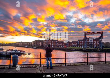 Sonnenaufgang am Preston Docks, Lancashire. Wetter in Großbritannien. 15 Jan, 2022., außergewöhnliche Cirrocumulus-Wolkenformationen, die sich an einem kalten Januarmorgen bei Sonnenaufgang in Preston-Docks bei kühltem Wind widerspiegeln. Cirrocumulus und Altocumulus rote Wolken enthalten überkühltes Wasser, das noch nicht zu Eiskristallen geworden ist. Das Wasser bleibt in der Atmosphäre schweben, bis sich schließlich Eiskristalle bilden und die umgebenden Wassertröpfchen verdunsten. Victoria Quay - Navigation Way Wohnungen in Docklands Reflexionen. Quelle: MediaWorldImages/AlamyLiveNews Stockfoto