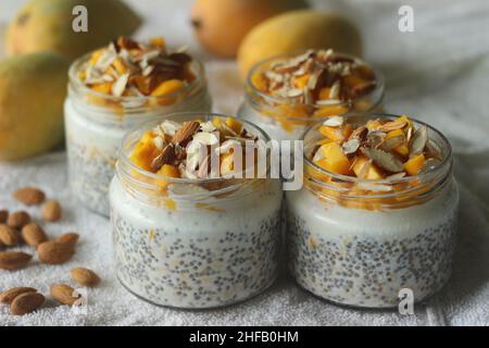 Über Nacht Hafer mit Mango und Mandeln. Hergestellt durch Einweichen gerollter Hafer und Chiasamen in Milch, serviert mit gehackten Mangos, Mandeln und Honig für einen gekühlten Stockfoto