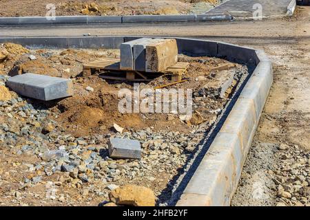 Bau der sekundären Straßenkreuzung und Installation von Bordstein mit Vorbereitung von Schotter Basis für Bürgersteig, selektive Fokus Stockfoto