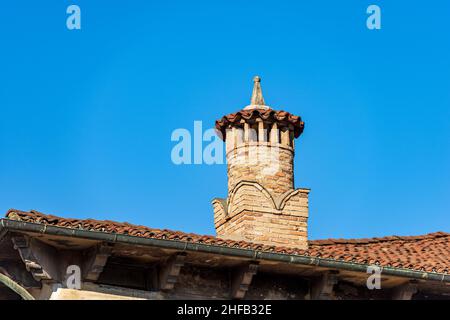 Nahaufnahme eines alten Schornsteins aus Ziegelsteinen auf einem klaren blauen Himmel, auf einem Dach mit Terrakotta-Fliesen (Coppo auf Italienisch). Vicenza, Italien, Europa. Stockfoto