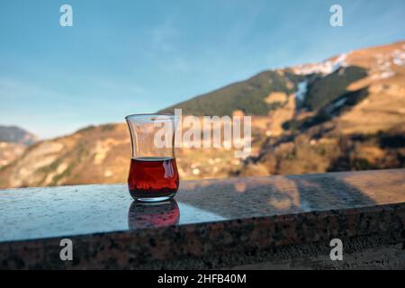 Tee und Spiegelung auf glänzender Oberfläche, halb gefüllter traditioneller türkischer Tee im Glashintergrund eines Hamsikoy, trabzon während der Wintersaison. Stockfoto