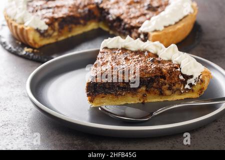 Stück Schokolade Walnüsse tart mit Schlagsahne close-up in einem Teller auf dem Tisch. Horizontal Stockfoto