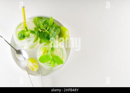 Mojito Cocktail mit Limette und Minze auf weißem Hintergrund. Werkzeuge zur Getränkeherstellung und Zutaten für Cocktails. Zwei Gläser Mojito auf einem weißen Teller. Oben Stockfoto