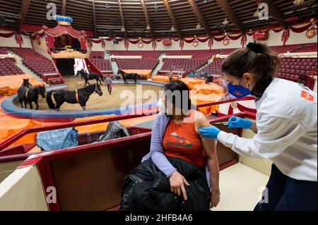 München, Deutschland. 15th Januar 2022. Die Vaccinologin Caroline Klima (r) impft im Circus Krone Paitul Supaporn gegen das Corona-Virus, während Pferde im Hintergrund im Ring trainieren. Kredit: Lennart Preiss/dpa/Alamy Live Nachrichten Stockfoto